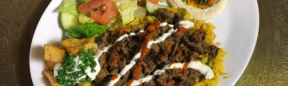 Beef shawarma platter over rice with salad, potatoes and hummus
